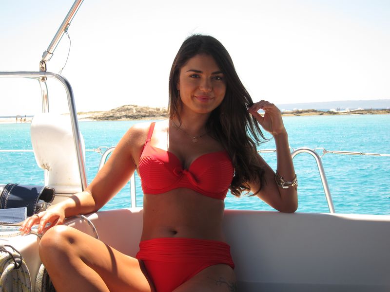 Alquiler de barcos en Ibiza modelos: una bella modelo descansa después de haber estado posando para las cámaras. Lleva un bello biquini rojo