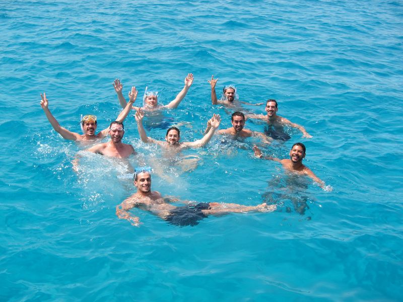A group of friends enjoy their luxury yacht charter Ibiza. They are posing while they are having a bath in a funny way