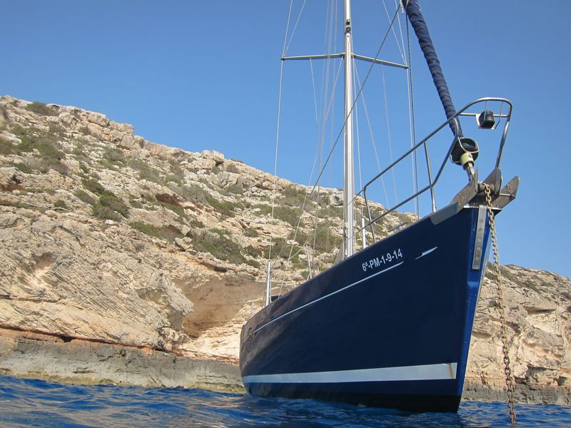 Ibiza boat trips caves: in the picture you can see a sailing boat anchored inf front of a cliff