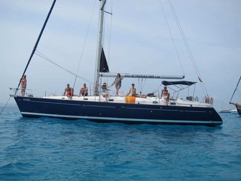 Un grupo de clientes disfruta de su alquiler velero con patrón Ibiza. Todos ellos posan en cubierta