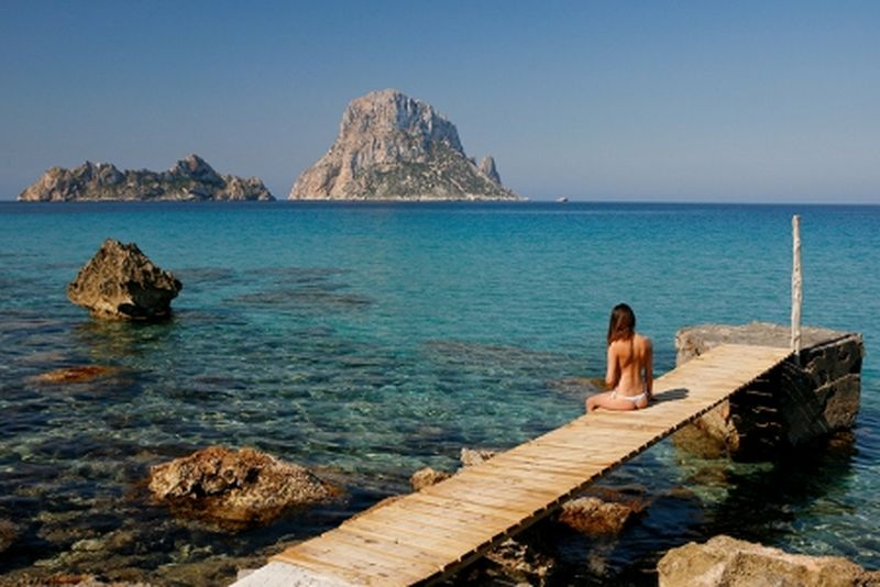 Las excursiones barco en Ibiza te trasladarán a lugares de incomparable belleza. En la imagen vemos a una joven disfrutando de las bellas vistas de Es Vedrà