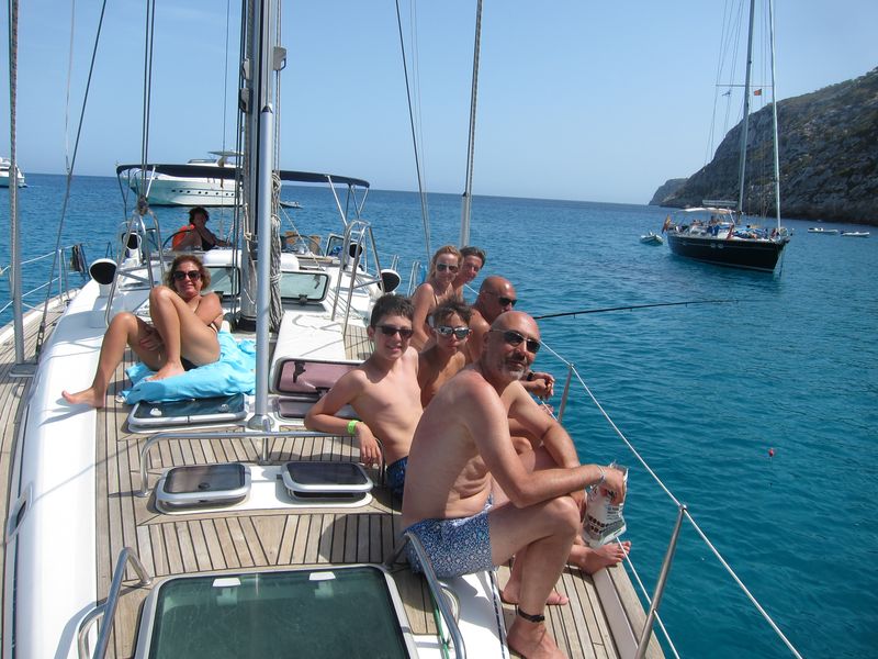 Un grupo disfruta de sus vacaciones en familia velero Ibiza. Algunos de ellos pescan y otros toman el sol en cubierta.